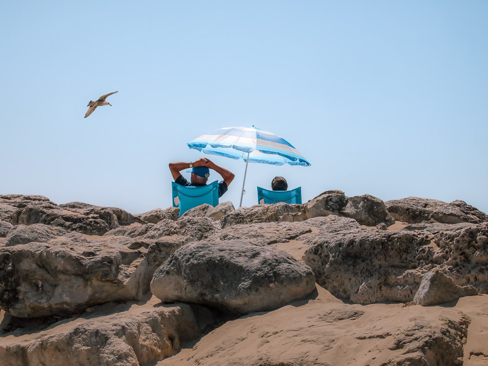 couple on beach with blue umbrella